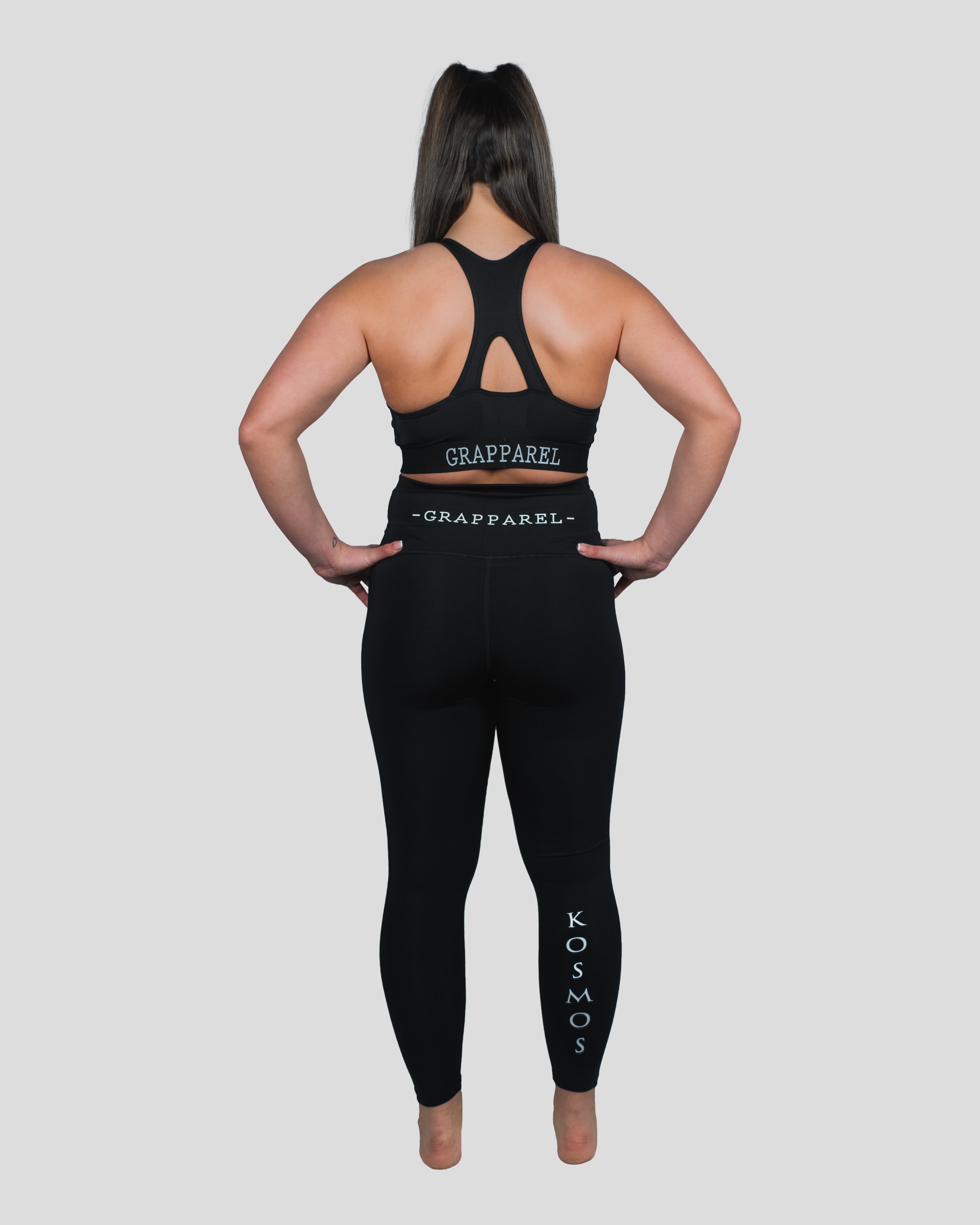 Woman modeling the Gorgo Spats from the back, featuring a racerback sports bra with "Grapparel" branding and high-waisted leggings for a complete activewear look
